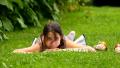Beautiful Girl Lying Down On The Grass In The Park, Looking At The Camera