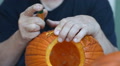 Man Carving Complex Design On Halloween Pumpkin