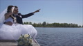 Newlyweds Sitting On A Wooden Bridge. Bride Groom Shows The Plane