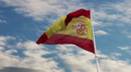 Spain Flag Waving In Blue Cloudscape Sky.
