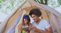 Couple On Camping Trip Using A Digital Tablet In Their Tent