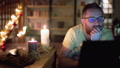 Pond5 Man relaxing at his christmassy house and browsing internet on laptop