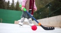 Happy Little Girl Stands On Skates With Hockey Stick At Rink