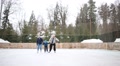 Two Men And Little Boy Skate Together At Ice Rink In Winter Day