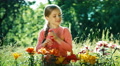Girl Sprinkling Flowers In The Garden And Smiling At Camera