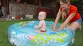 Mother Splashing Water With Her 1 Year Old Baby Boy At Inflatable Swimming Pool