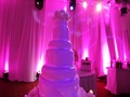 Wedding Cake Decorated With Flowers In Pink Spotlights. Crane Shot.