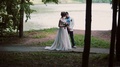 Couple In Love On A River Bank On Their Wedding Day. Happy Bride Turns And Shows
