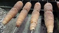 Rotisserie Of Buns On Some Metal Spits In An Open Oven In Some Street In Europe
