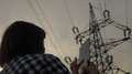 Girl Use Mobile Phone On Background Supports High-Voltage Power Lines