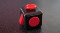 Red And Black Fidget Cube On Black Table Top, Focus Pull