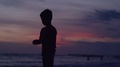 Silhouette Of Boy Standing On Beach During Sunset, Super Slow Motion 240fps