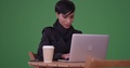 Fashionable Woman Using Laptop Computer At A Caf Table On Green Screen