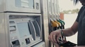 Man Operating Fuel Pump Payment Kiosk, Tourist Pay Card On Gasoline Station