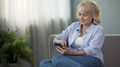 Joyful Mature Woman Scrolling News In Social Media On Smartphone At Home, App