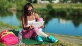 Girl Sits Near Lake And Talks Via Tablet Pc