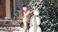 Christmas Or New Year. The Child Adjusts His Hat And Scarf On The Snowman