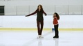 Female Athlete Teaching Girl How To Spin On Ice