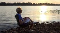 Young Man Does A Relaxing Exercise In A Folding Chair At Sunset