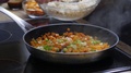 Rice Being Added Into A Frying Pan With Sauteed Carrots And Spring Onions