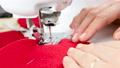 Woman Sews A Red Fleece Heart Toy With A Modern Sewing Machine