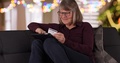 Happy Mature Lady On Couch Holiday Shopping Online With Portable Tablet Device