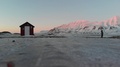 Longyearbyen, Svalbard Woman Standing Next To Cabin And Frozen Arctic Sea Enj