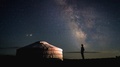 Cinemagraph Of Man Standing By Yurt Looking At Stars In Night Sky