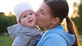 A Mother Kisses Her Cute Baby Many Times In The Park At Sunset. Slowmotion
