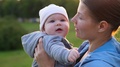 A Mother Kisses Her Baby Many Times During The Sunset. Slowmotion
