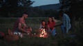 Group Of People Near Camp Fire With Campfire Meals, Playing Campfire Games And