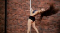 Young Woman Dancing Pole Dance In The Studio. Flying Hair