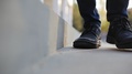 Man In Boots Walking On The Concrete Stairs And Stops Near The Camera In Focus