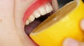 Woman's Mouth With Bright Red Lips Bites Off A Piece Of Yellow Juicy Lemon.