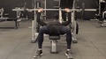 Young Man Doing Bench Press With Barbell In Gym. Front View
