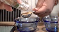Woman Shaking Ground Cumin Into Tablespoon And Pouring Into Bowl, Close Up