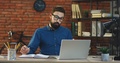 Caucasian Stylish Male Office Worker In Glasses And With A Beard Sitting At The