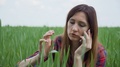 Woman In Plaid Shirt Sitting In Field Of Grain And Talking On Mobile Phone And