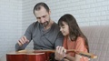 Father Teaches Teen Daughter To Play The Guitar.