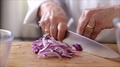 Chef In Kitchen Slicing Red Onion.