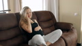 Young Pregnant Woman Talking On Phone Sitting On The Sofa.