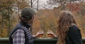 Couple Watching The Leaves Fall Off The Trees From A Deck In The Autumn