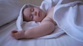 A Cute Naked Child Sleeps With His Hands Up On A Large Bed In Slow Motion