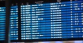 Blonde Girl Checks Her Flight Ticket With Scoreboard In Big Modern Airport. Big