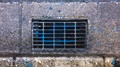Rain Water Pouring Down Metal Drain Cover In Street Gutter. Overhead Shot