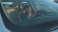 Positive Young Man Using Mobile Phone In The Car Crying With Laughter Reading