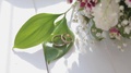 Close Up Wedding Rings, White Roses And Lilac Flowers. Wedding Concept