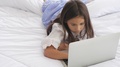 Cute Caucasian Girl Lying And Using Laptop On Bed Happily In Morning At Home