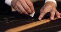 Close Up Footage Of A Tailor Drawing Lines On Fabric And Making Some Alterations