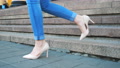 Female Legs In Jeans And Trendy High Heels Shoes Going Down On Stairs. Slim Feet